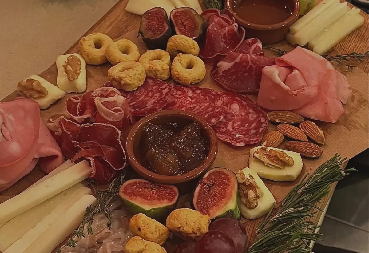 Tabla de embutidos y quesos variada, con jamones, salchichones, diferentes tipos de quesos, frutos secos, higos y salsas, ideal para compartir en reuniones y celebraciones.