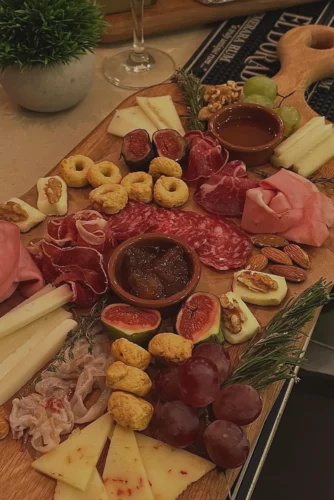 Tabla de embutidos y quesos variada, con jamones, salchichones, diferentes tipos de quesos, frutos secos, higos y salsas, ideal para compartir en reuniones y celebraciones.